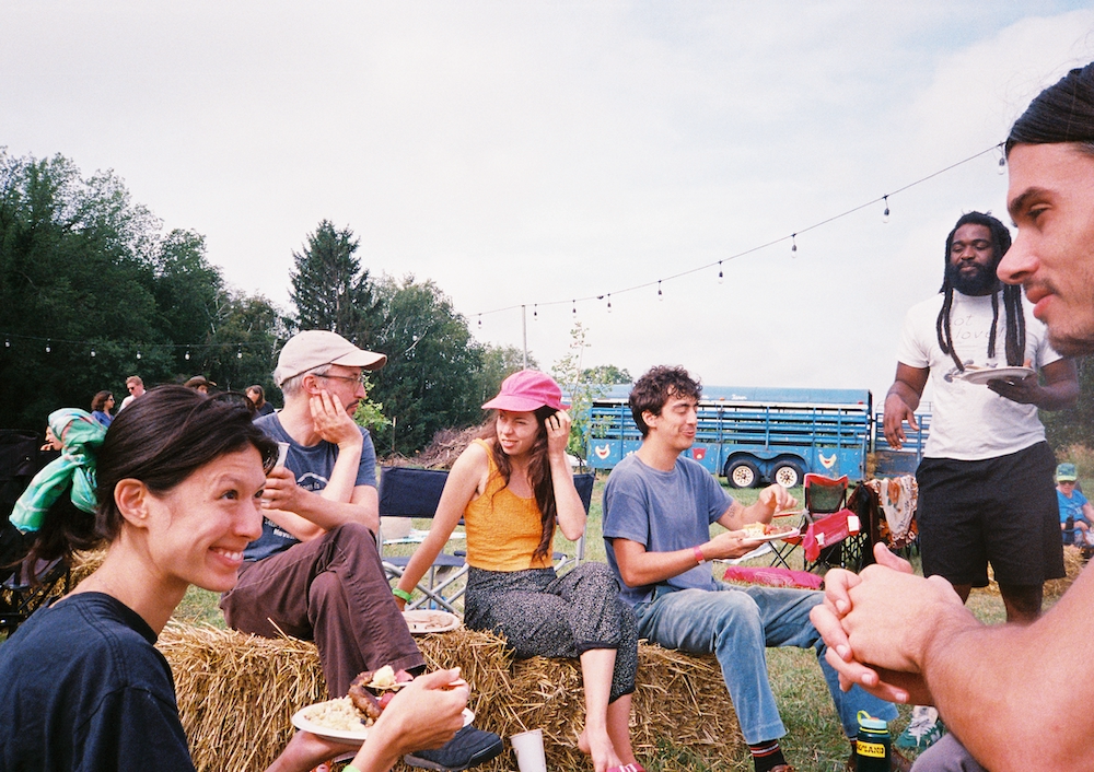 Farm festival attendees sit on haybales and talk.